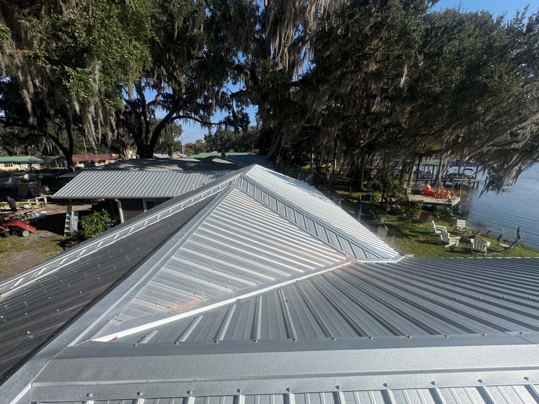 Aerial view of newly installed silver standing seam metal hip roof on lakefront Florida home