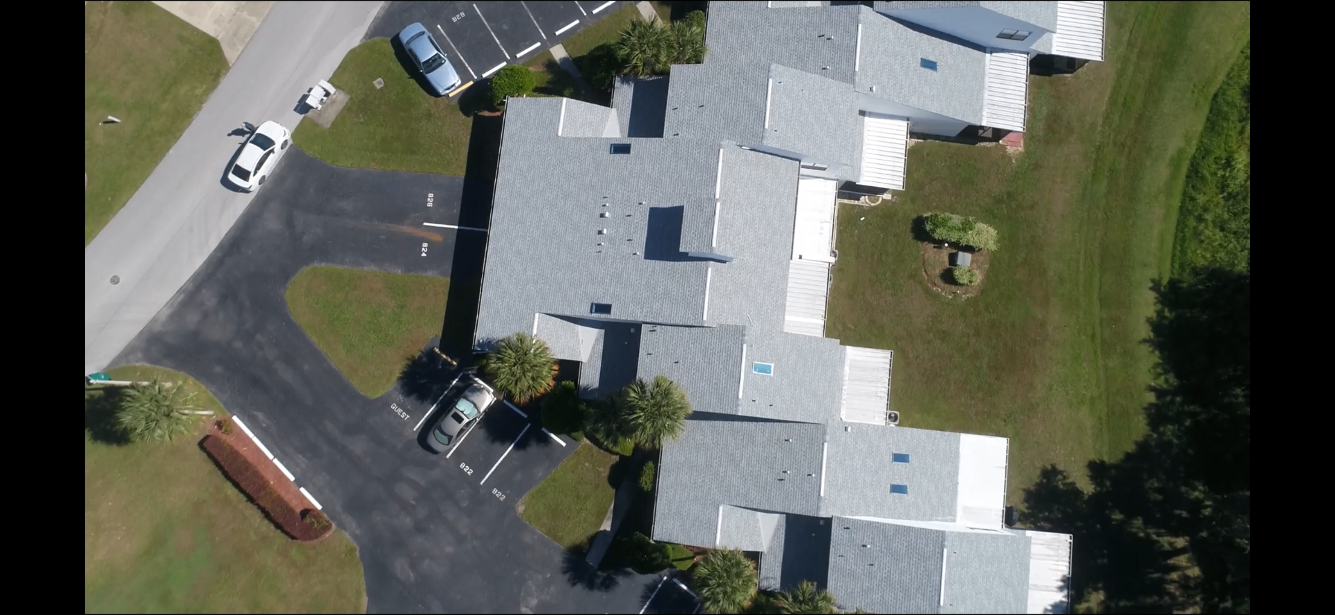 Top-down aerial view of multi-unit Florida condo building with new light grey architectural shingle roof