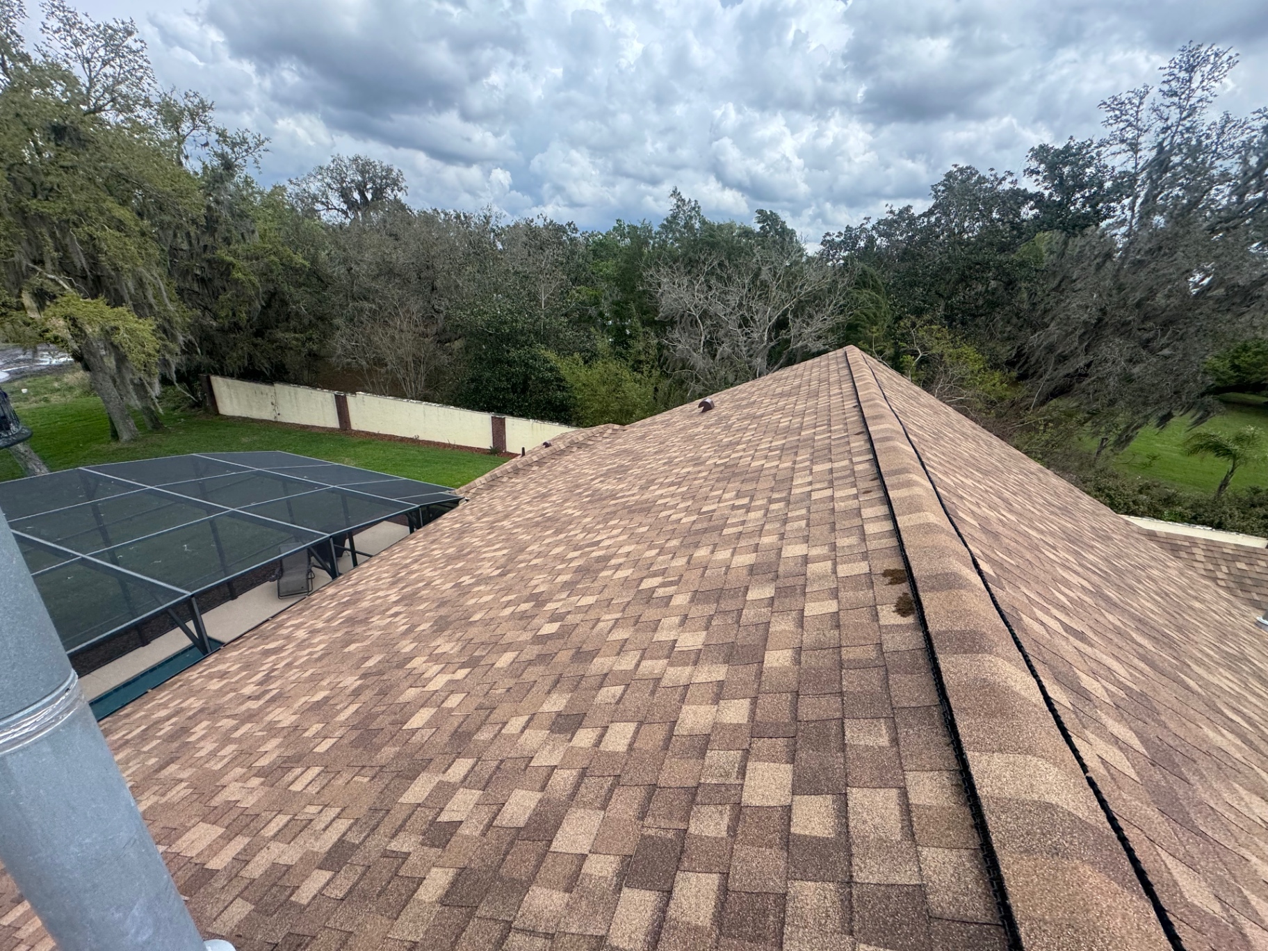 Hip roof with desert-tan architectural shingles overlooking screened pool enclosure