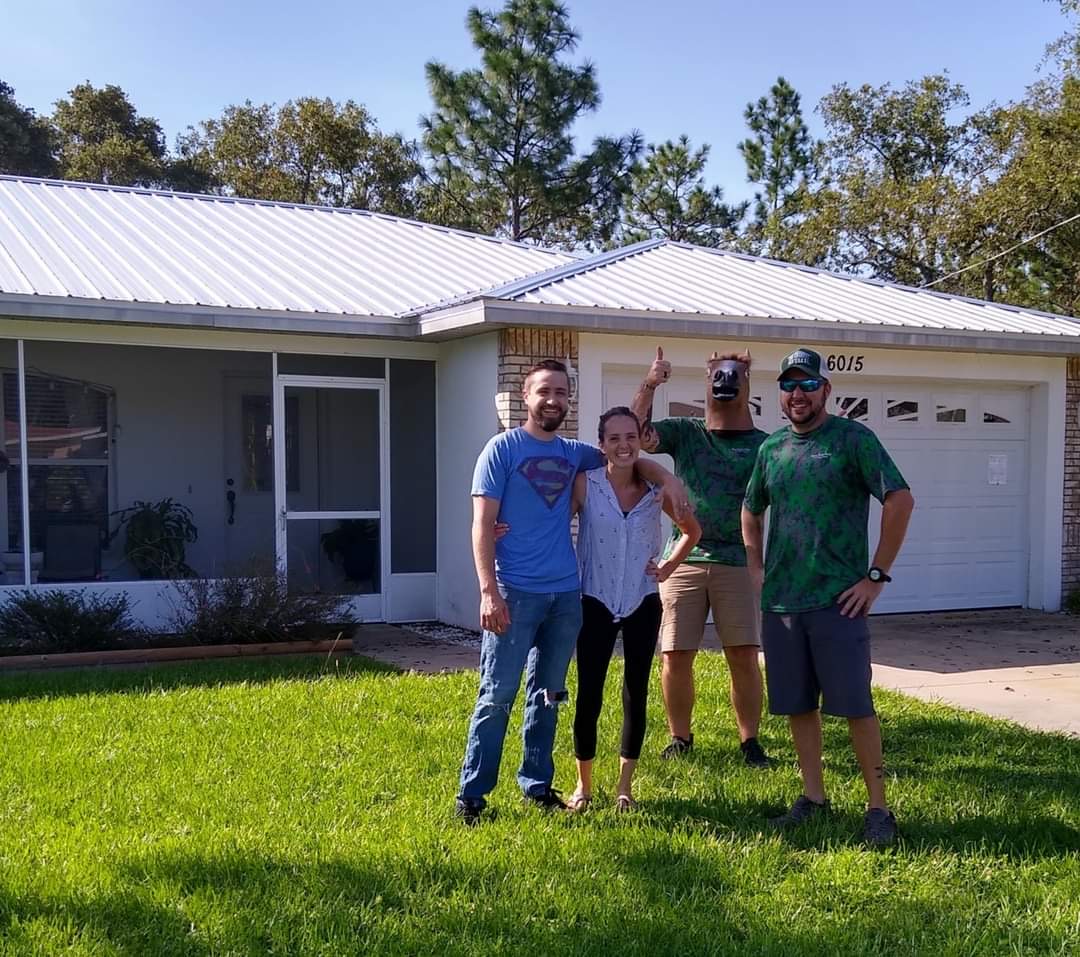 Happy homeowners in front of newly installed standing seam metal roof in Citrus County, FL